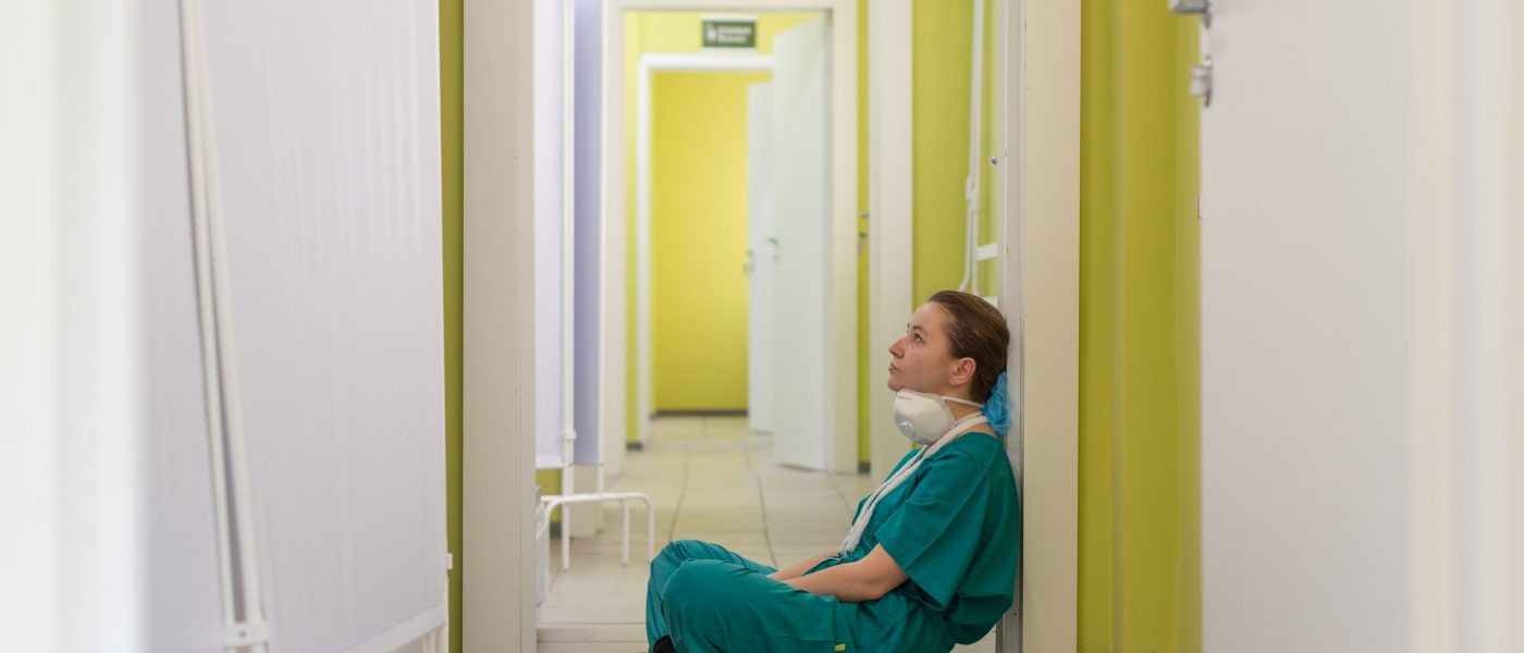 Tired nurse worker in hallway A tired nurse sits on the floor of a hallway