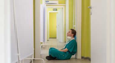Tired nurse worker in hallway A tired nurse sits on the floor of a hallway
